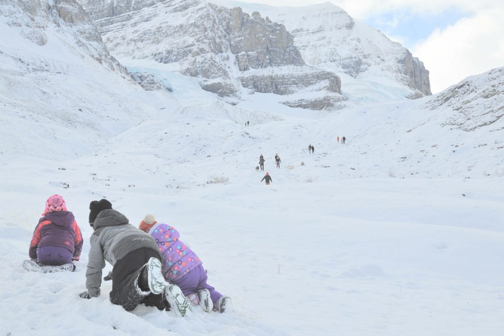 kids crawling through the snow, mountains and glaciers in the background