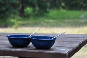 two blue metal camping bowls sitting on a picnic table