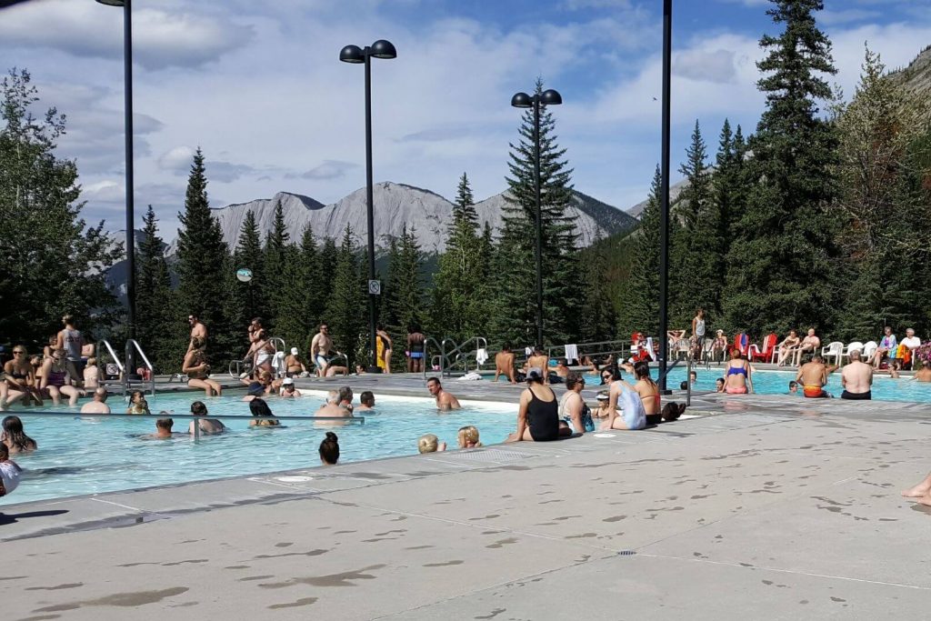 People enjoying the pools at the Miette Hot Springs in Jasper National Park, mountains visible in the background