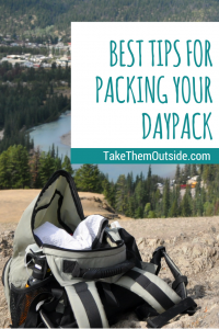 an open daypack sitting on some rocks overlooking a river and town, text reads best tips for packing your daypack