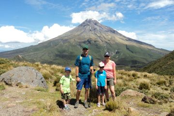 Connect your family to nature: Man, woman, and two children standing together with Mt. Taranaki of New Zealand in the background. text reads making nature connections, one family's story