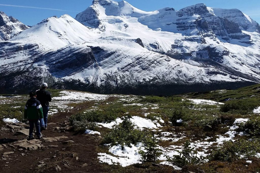 a dad and kids hiking with snowy mountains in the distance