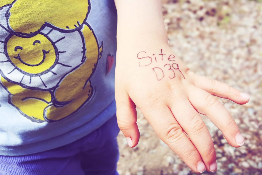 Toddler's hand with a campsite number written on it