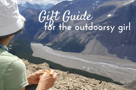 a woman looking out over a mountain valley, text reads gift guide for the outdoorsy girl