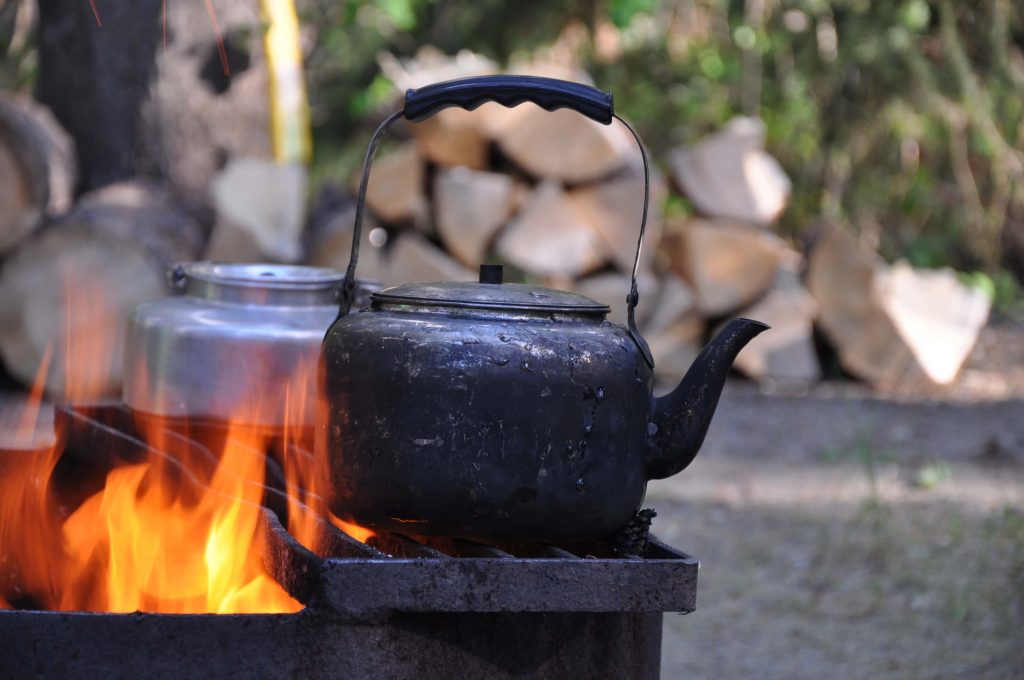 boiling water over a campfire with camp kettles