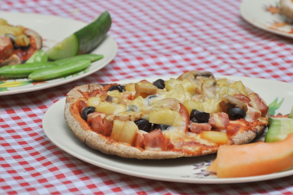 a cooked pita pizza siting on a red checkered picnic table