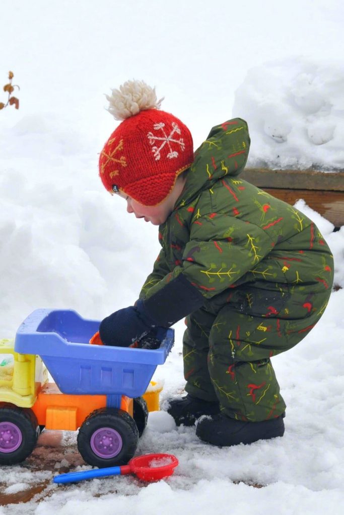 a toddler wearing a one-piece snowsuit to stay warm in the snow