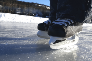 a close up of kid's hockey skates on a frozen lake