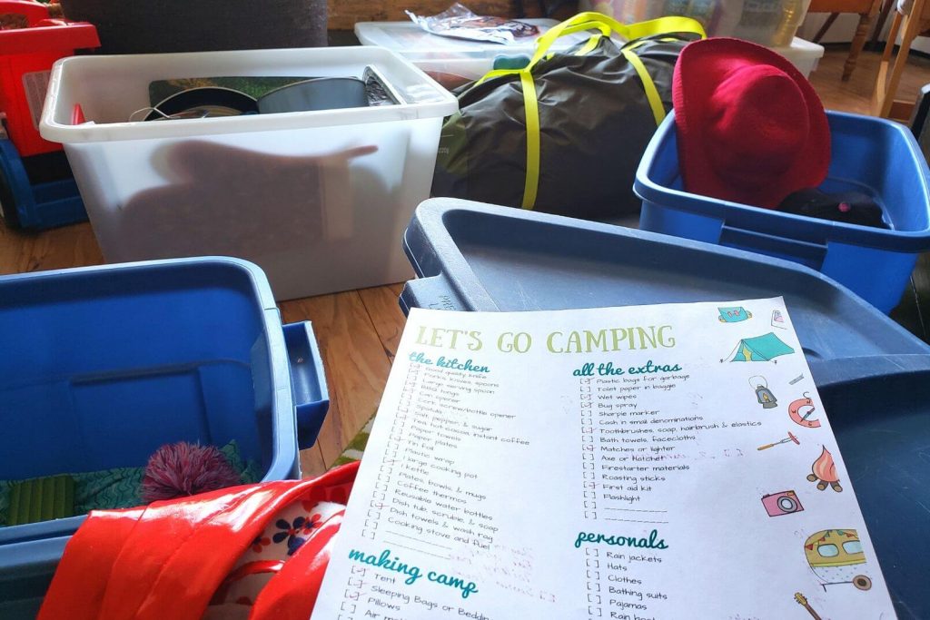 a printed family camping checklist being used to pack for a camping trip