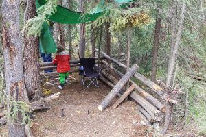 a young kid playing in a wooden shelter at the campsite
