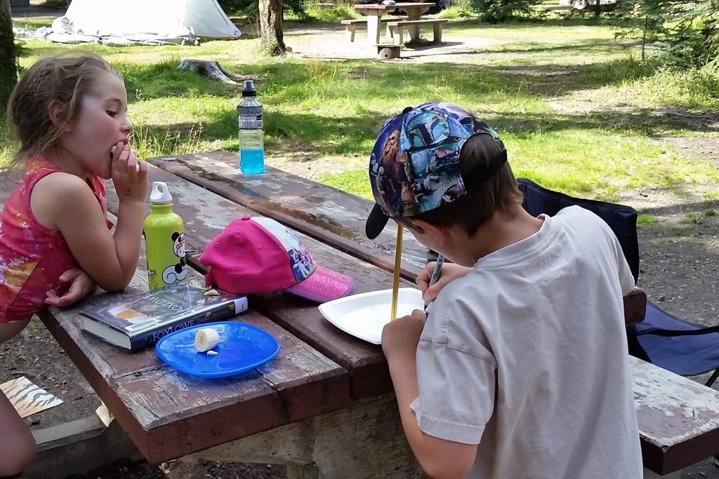 kids doing quiet activities at the campsite picnic table