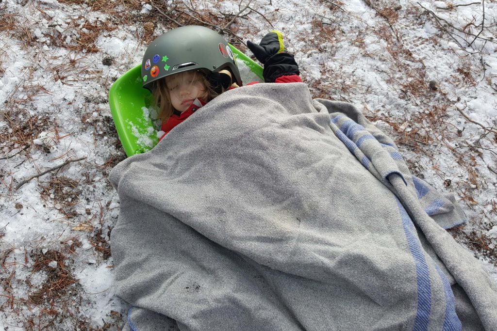 a toddler wearing a ski helmet asleep outdoors in the winter