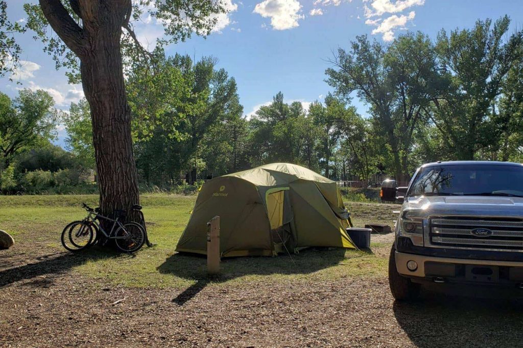 a tent and truck on at open grassy campground 