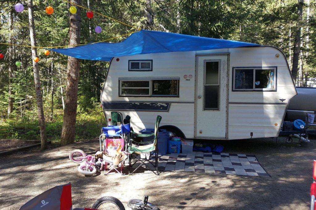 A family set up at the campground with a vintage trailer, some bikes, and toys