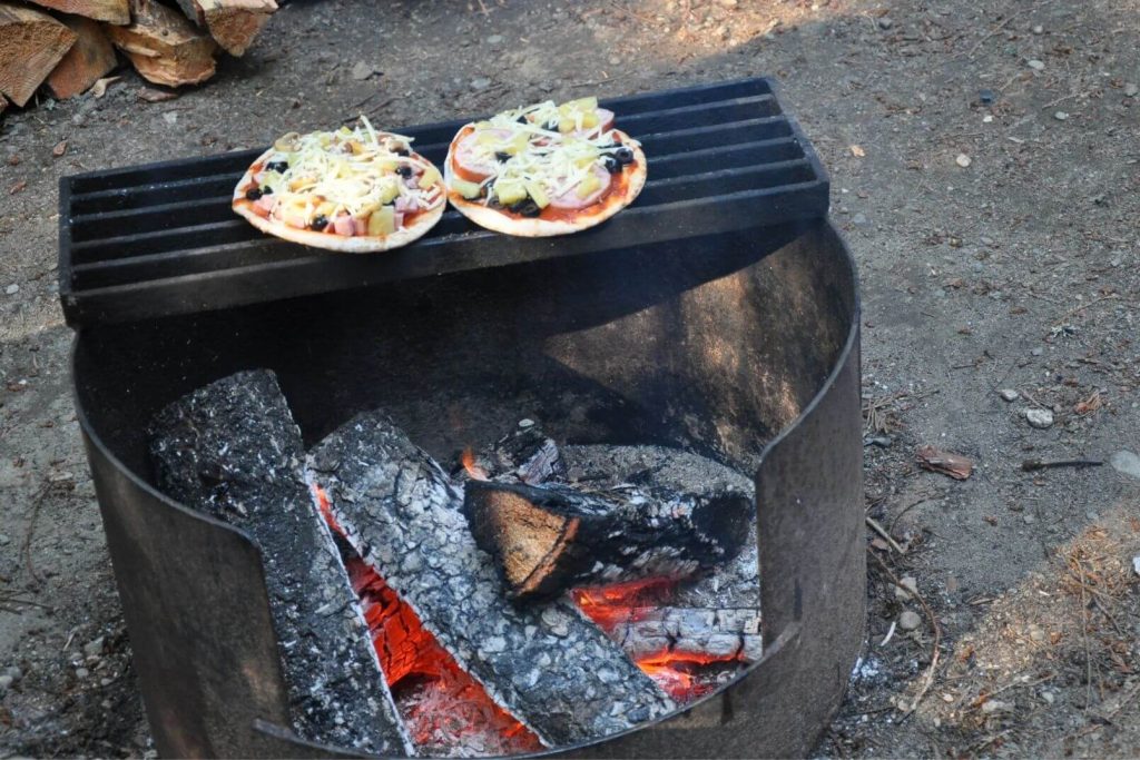 cooking pita pizzas on a grill over the campfire