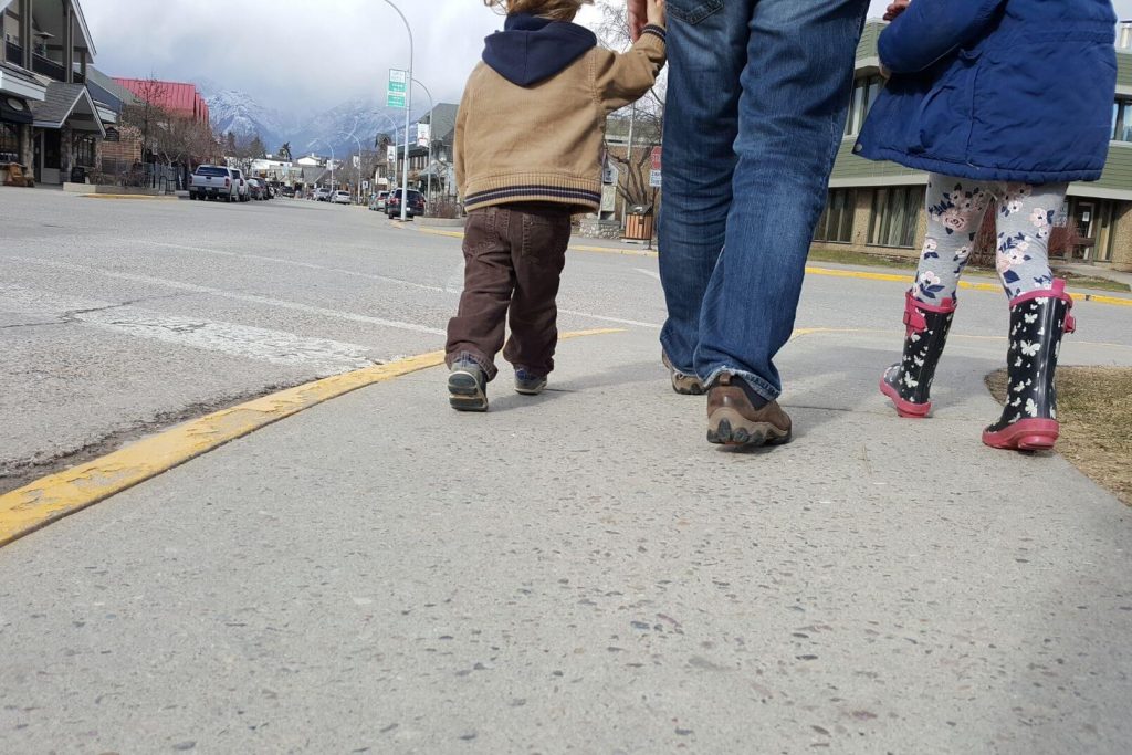 A family walking on the sidewalk going on a neighborhood scavenger hunt