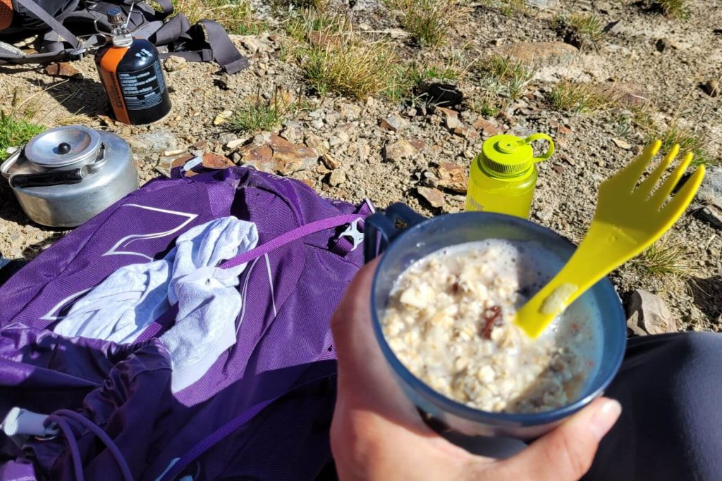 eating instant oatmeal out of a blue cup while hiking