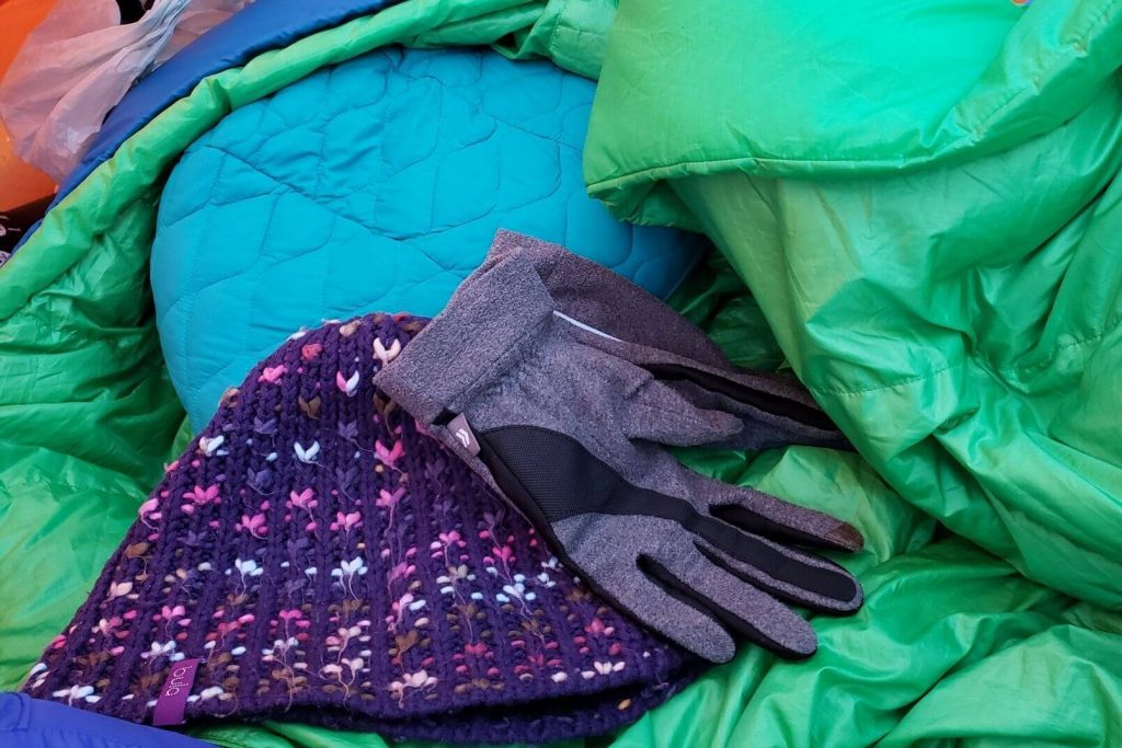a toque, gloves, and down sleeping bag that help keep you stay warm when camping in a tent
