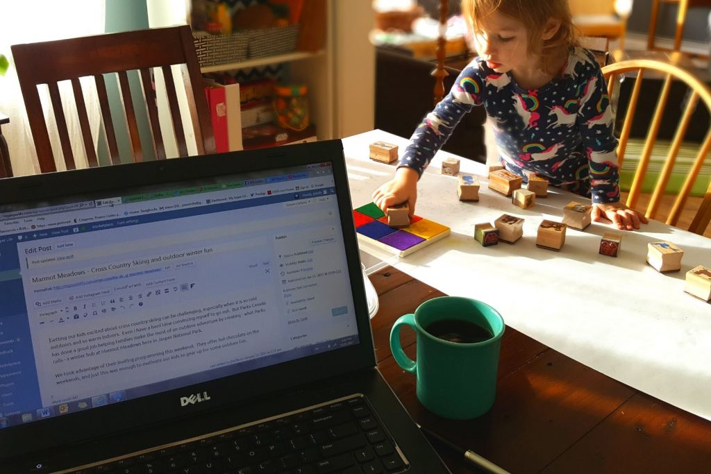 a toddler playing quietly while mom works nearby on the computer