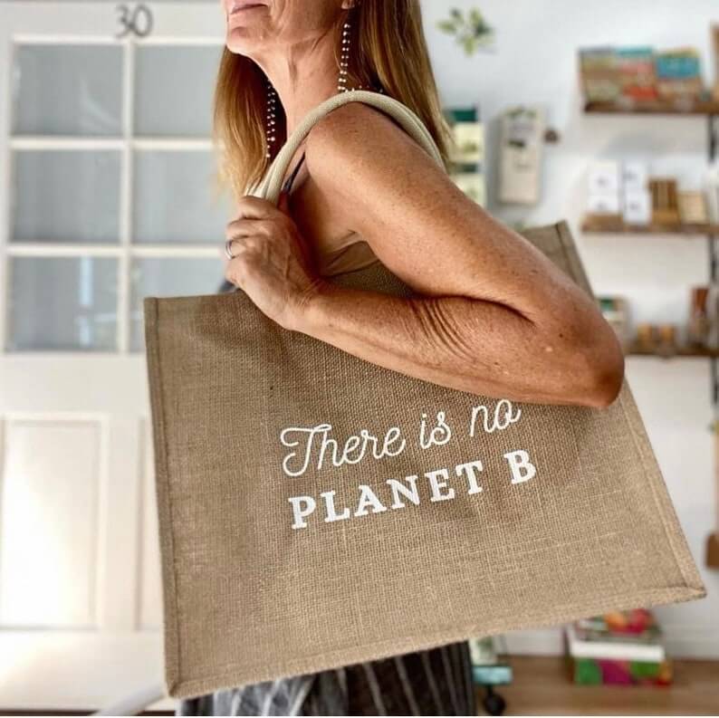 a woman holding an eco friendly reusable jute tote bag