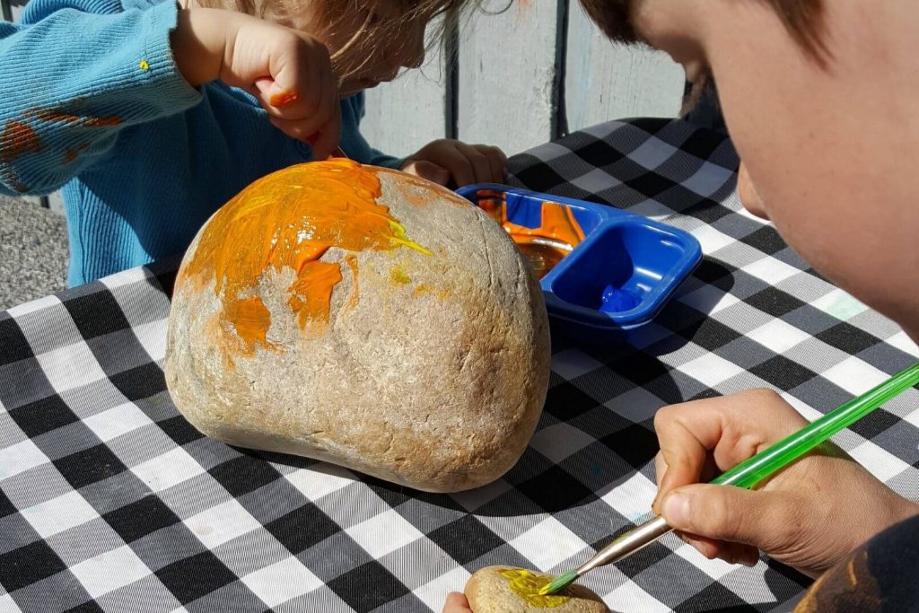two kids outside painting rocks for the garden