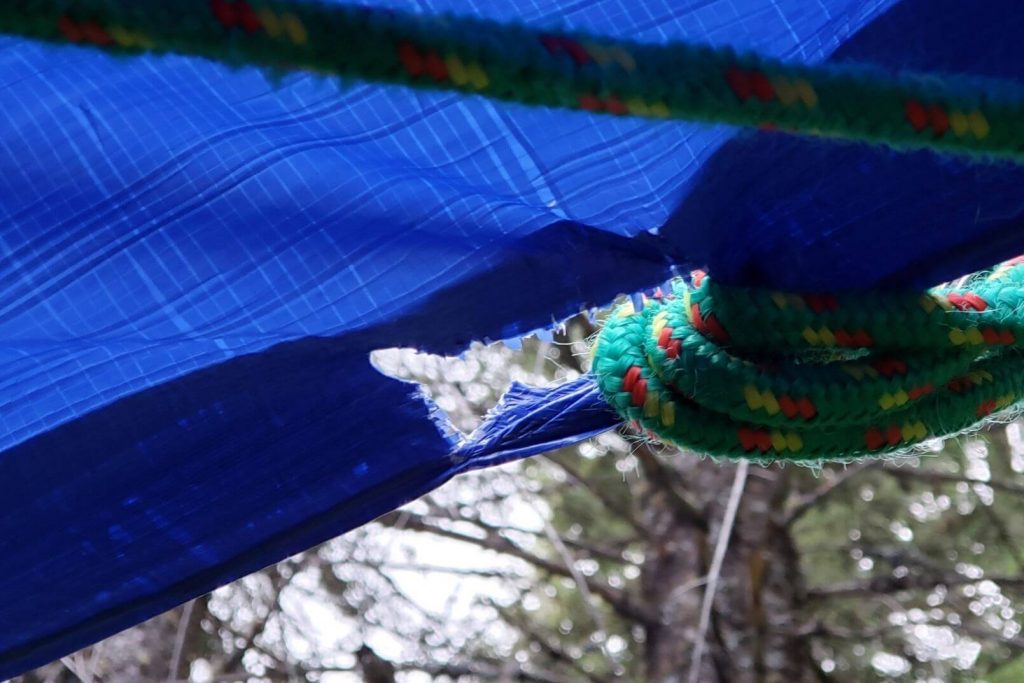 A rip in a blue camping tarp