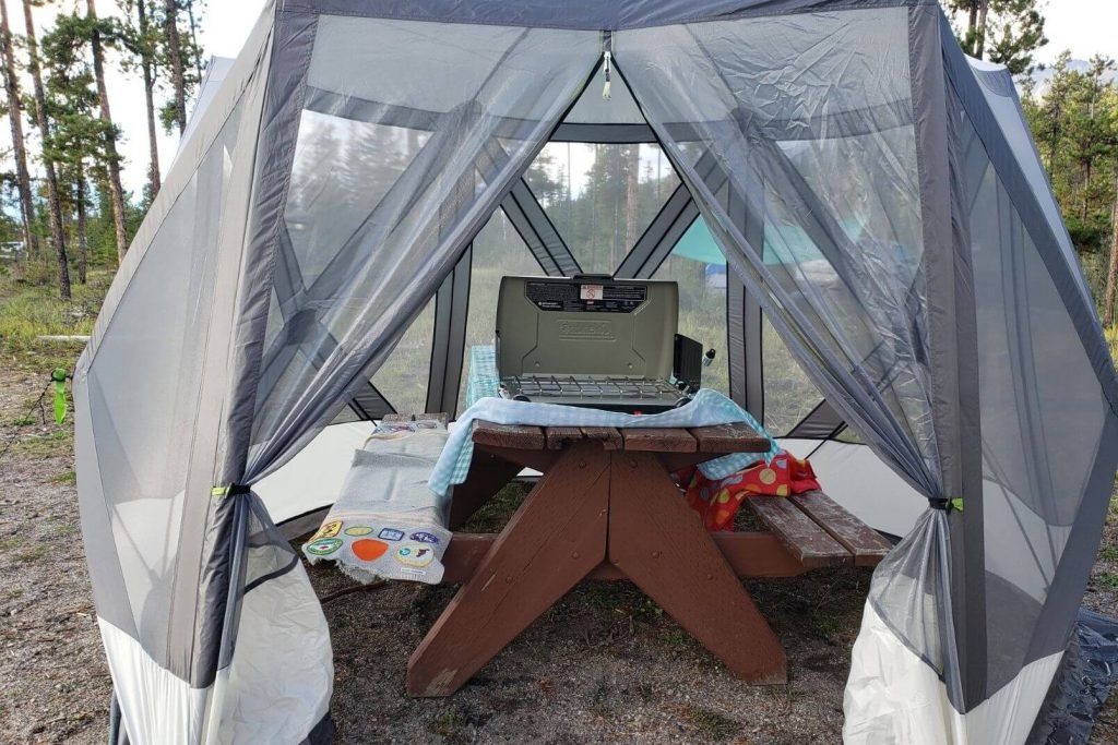 a pop up shelter set up over a picnic table to provide shelter from rain