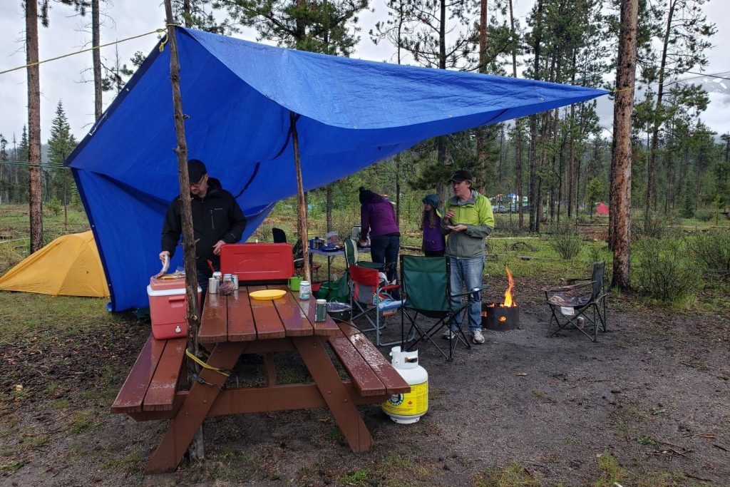 a large blue tarp set up over the campfire and outdoor camp kitchen area