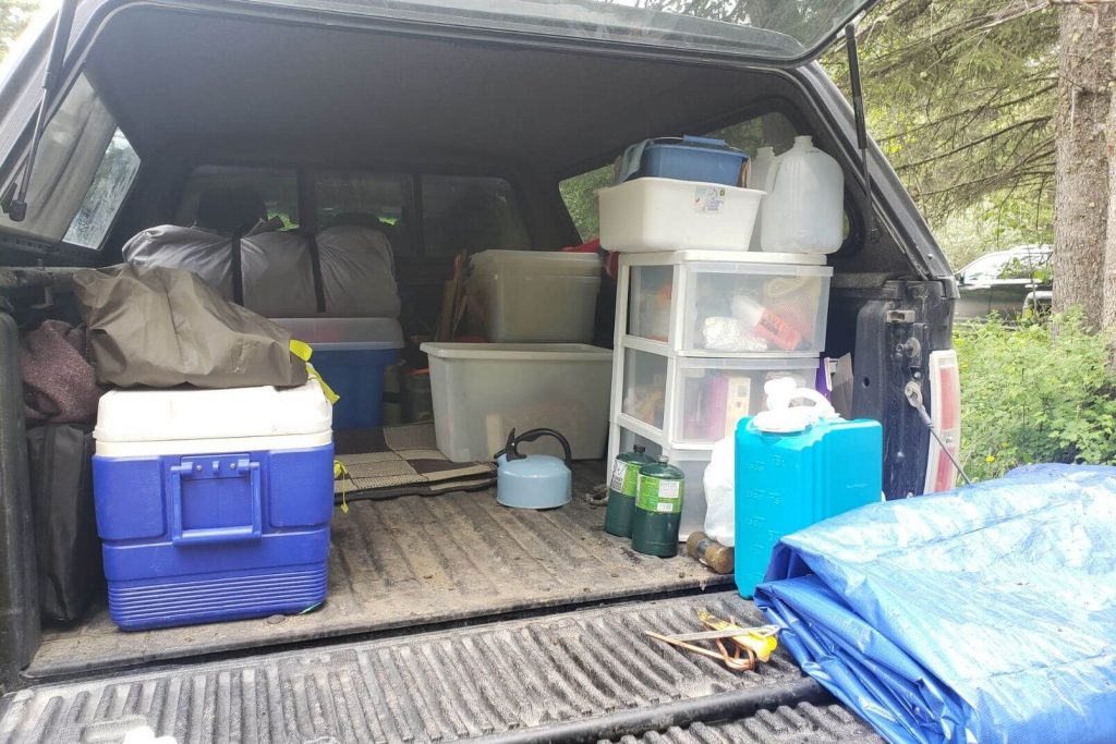 the back of a truck organized with tubs and camping gear