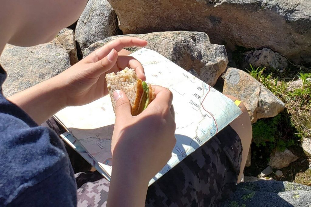 a kid eating a sandwich while looking at a map