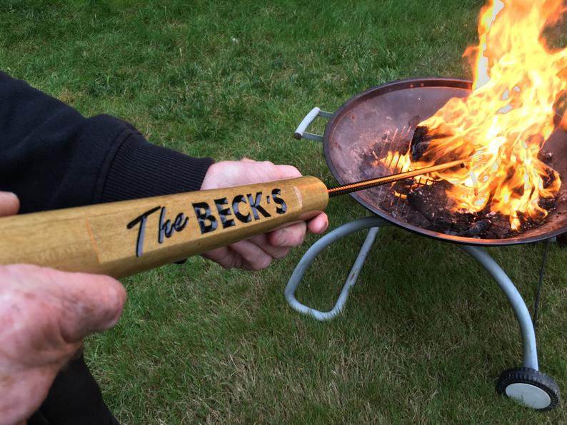 a handmade personalized fire poker stick being used in a campfire