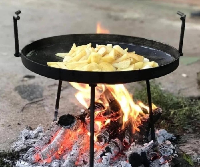 a handmade skillet being used to cook food over a campfire