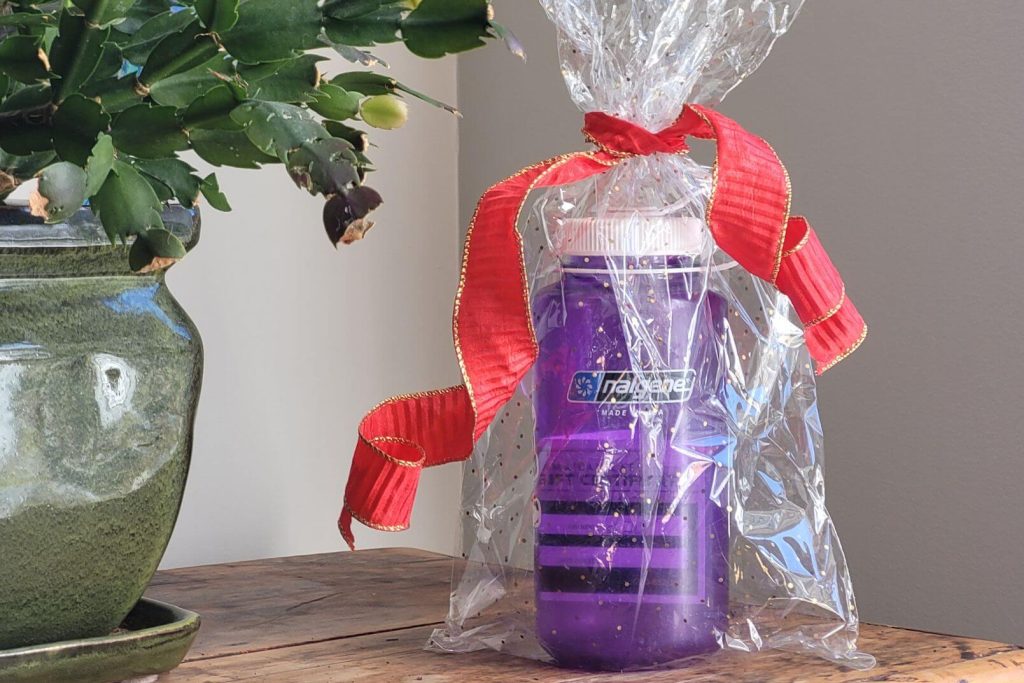 A Nalgene bottle with a gift certificate inside wrapped with a bow ready for gift giving