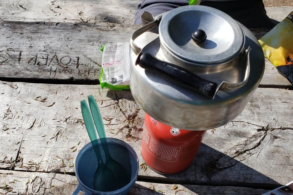camping kettle on a single burner camping stove, boiling water at the campsite