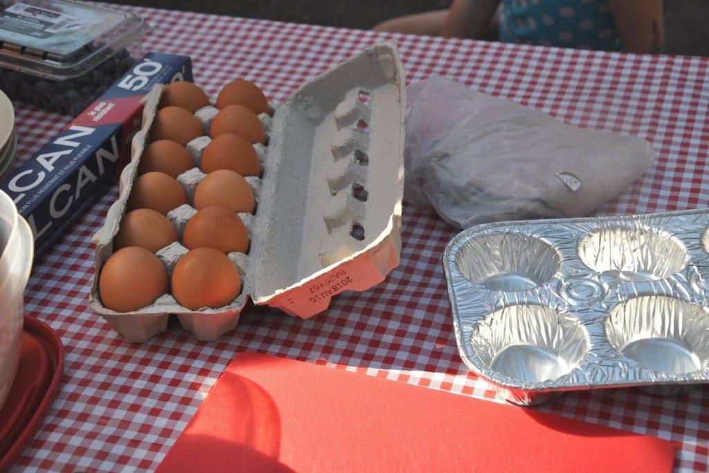 eggs, ham, and muffin tins on a picnic table