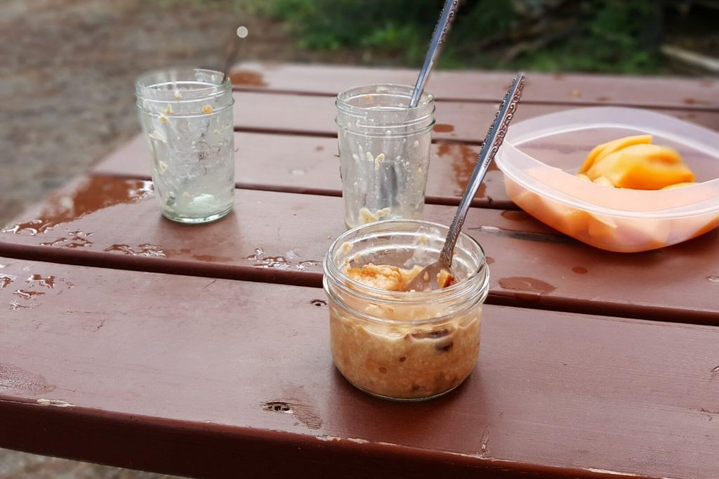 a breakfast of oatmeal and fruit on a picnic table