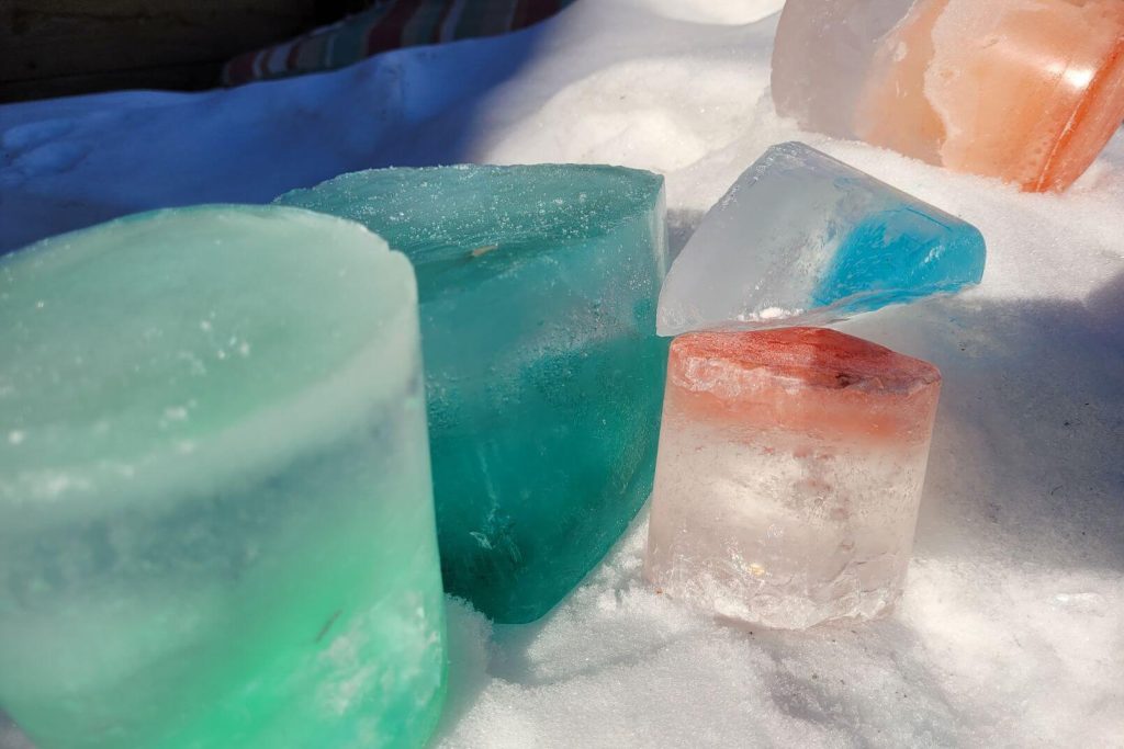 frozen ice blocks filled with colored water sitting on the snow